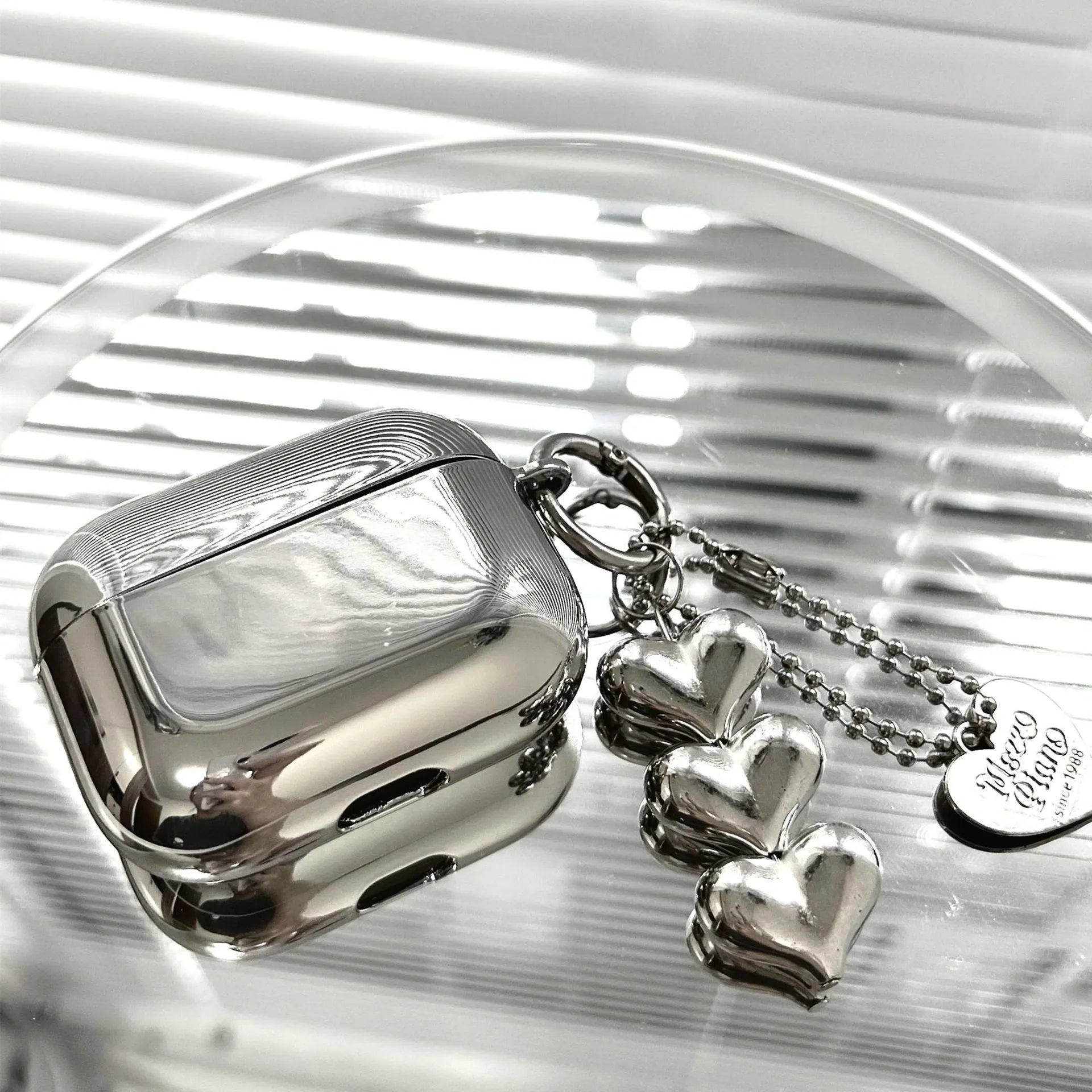 Electroplated solid colour TPU headphone case with heart pendant charms and chain for Apple earbuds.