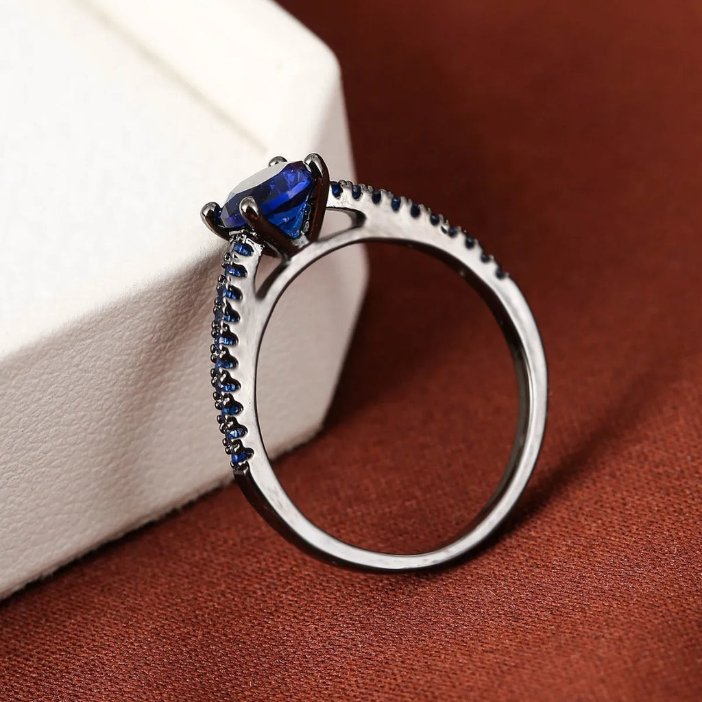 A geometric hexagonal copper ring with a central zircon stone, shown in a gun black and rose red electroplated finish.