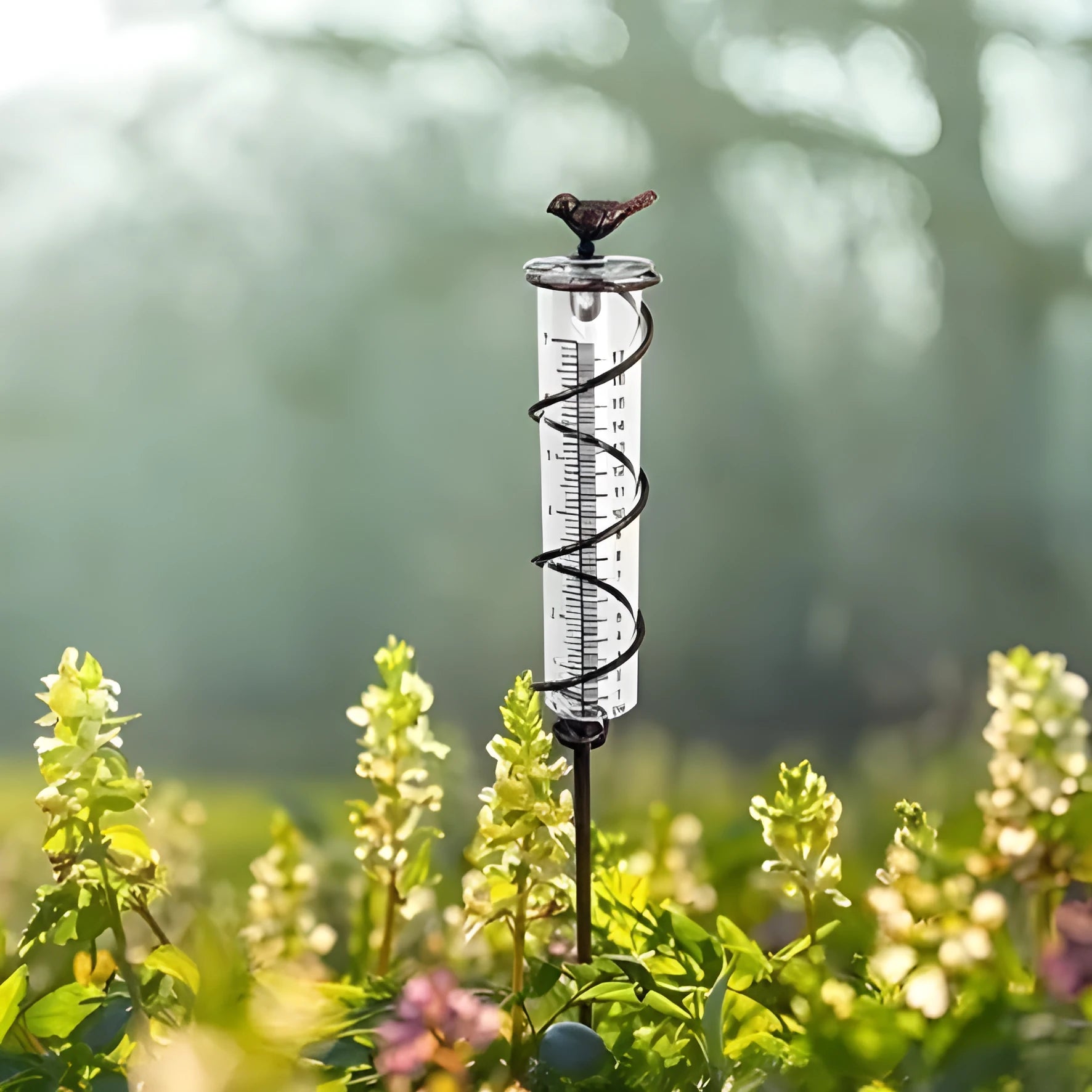 Cast iron hummingbird garden rain gauge with glass measurement tube showing 1-20 scale.