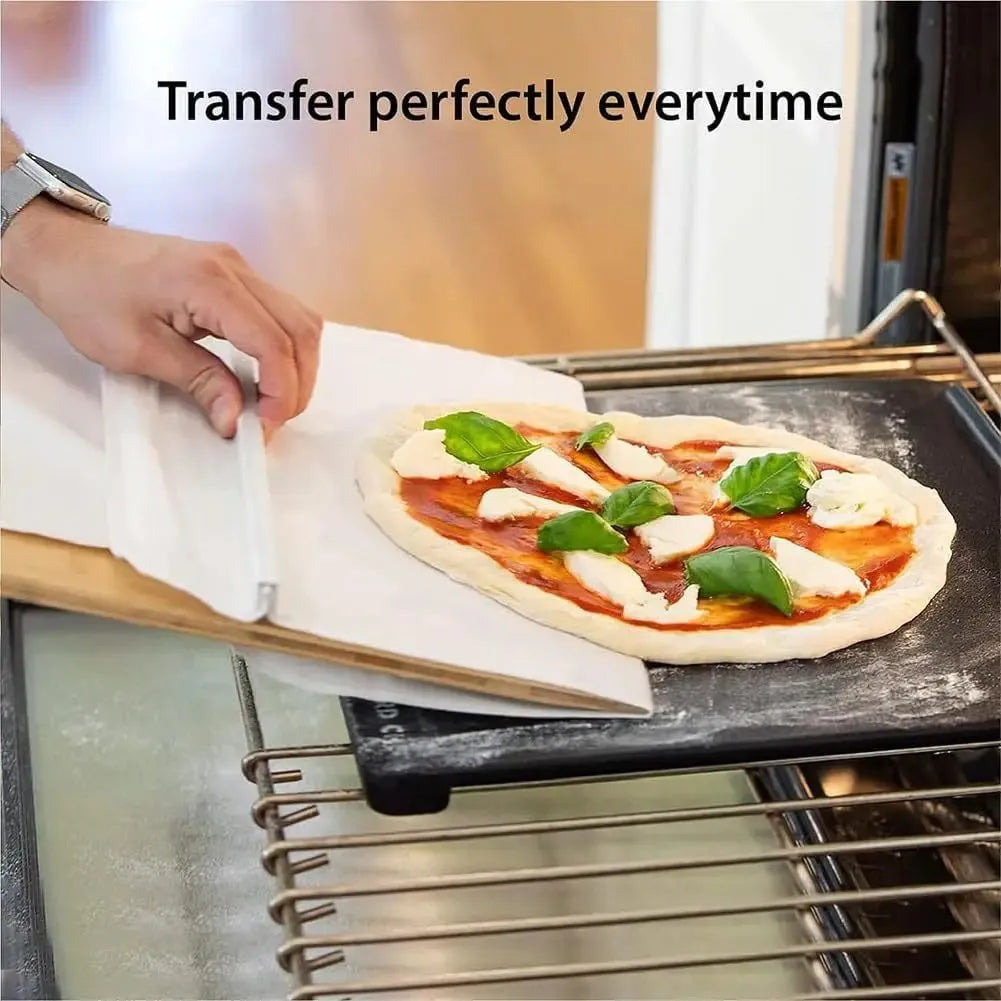 White plastic pizza transfer shovel on a kitchen counter, showing its flat board surface and handle with hanging hole.