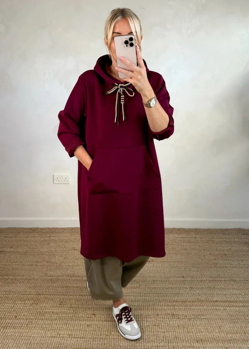 Woman wearing loose oversized knit hooded maxi dress in solid colour with front pockets, pullover style, black colour option