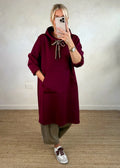Woman wearing loose oversized knit hooded maxi dress in solid colour with front pockets, pullover style, black colour option