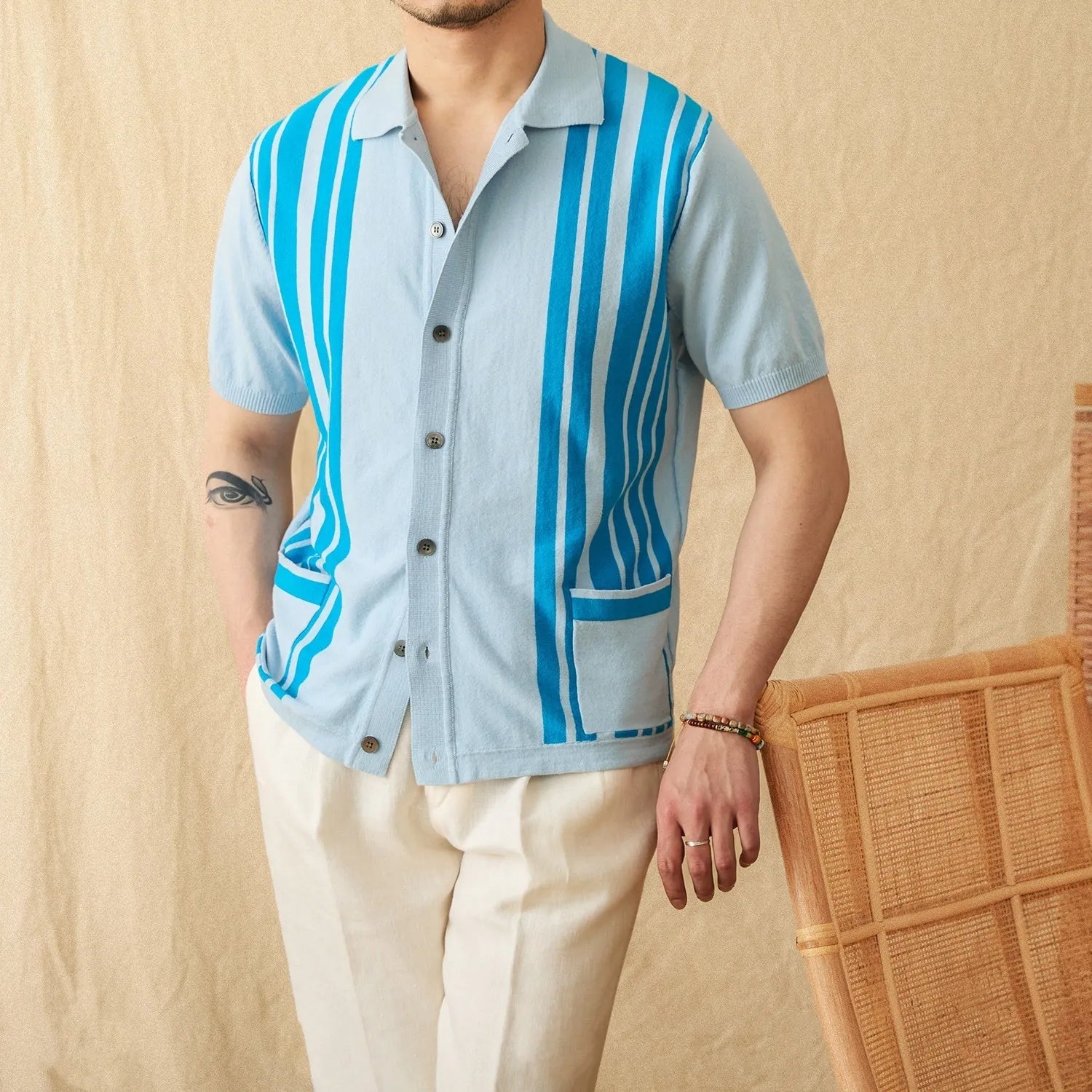 Man wearing a royal blue striped short-sleeved knitted polo cardigan with a lapel collar.