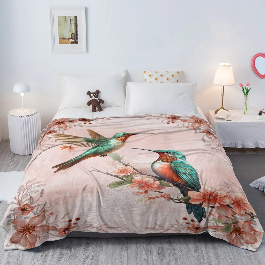 Pink hummingbird floral fleece throw blanket on sofa with floral print