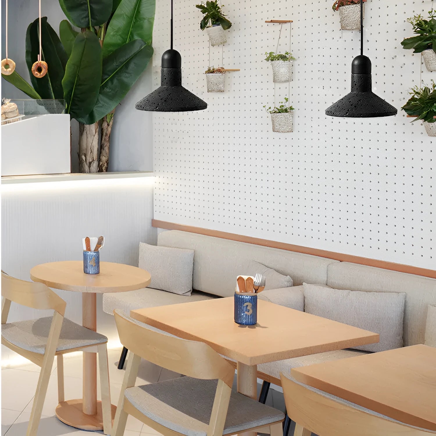 Industrial style black iron chandelier light hanging above a wooden bar table.