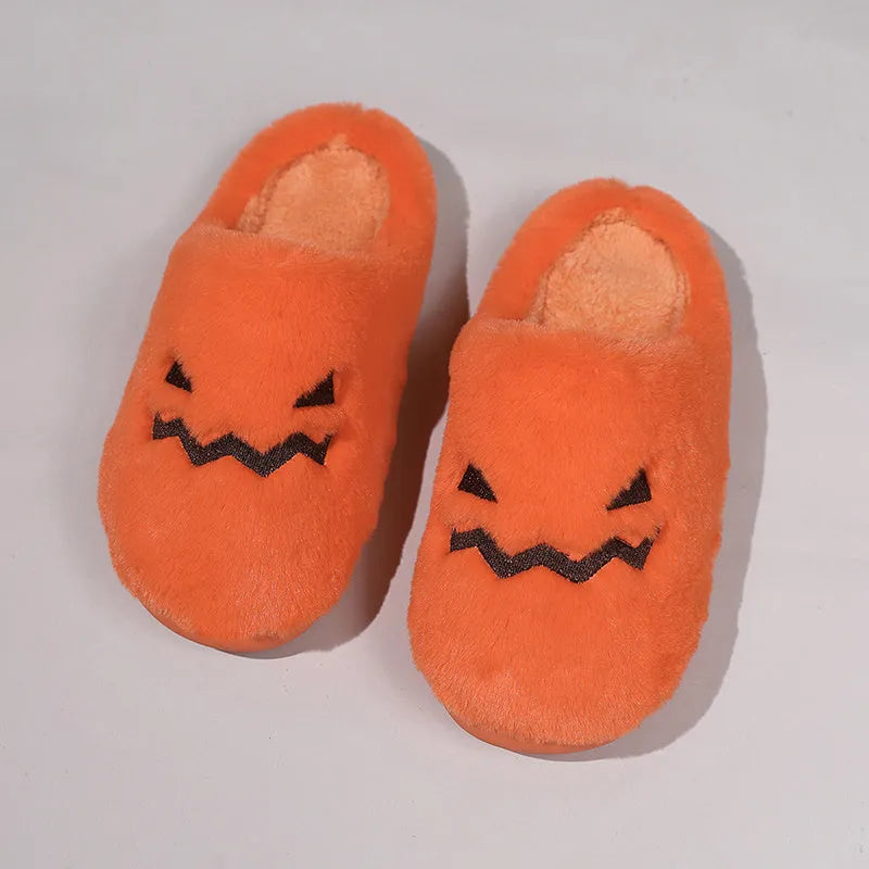 Orange Halloween pumpkin-themed plush indoor slippers with a non-slip sole on a wooden floor.