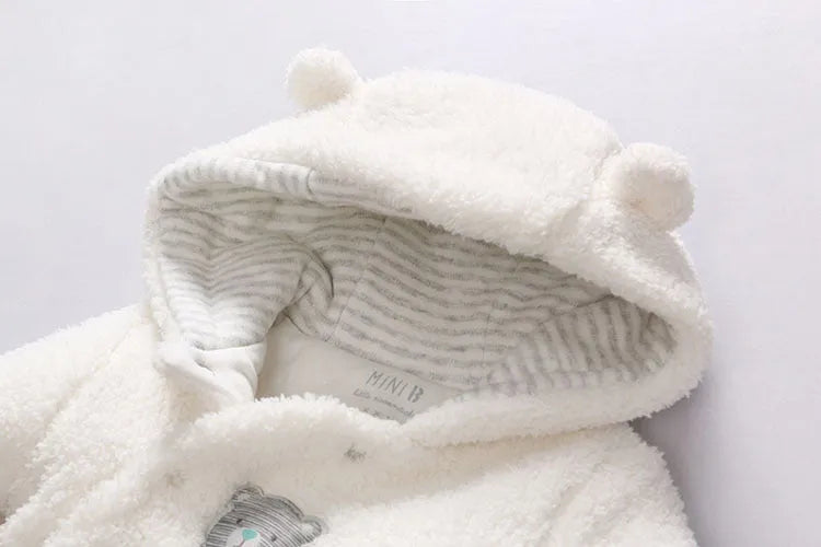 Baby wearing a cosy white cotton padded lamb-themed winter bodysuit with long sleeves.