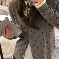 Grey dot pattern women's knitted cardigan with crochet flower detail on a hanger.
