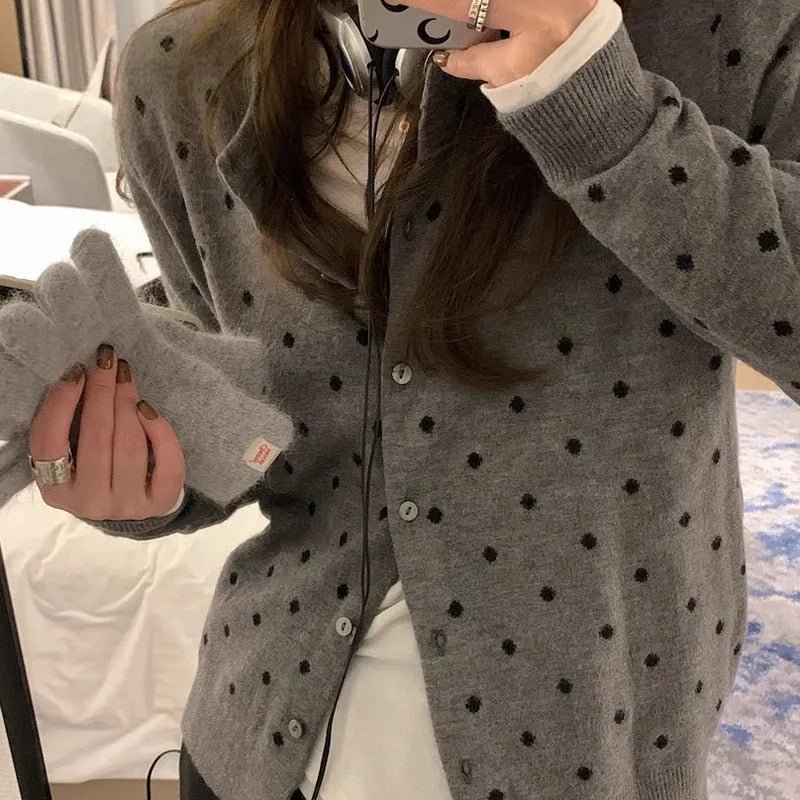 Grey dot pattern women's knitted cardigan with crochet flower detail on a hanger.