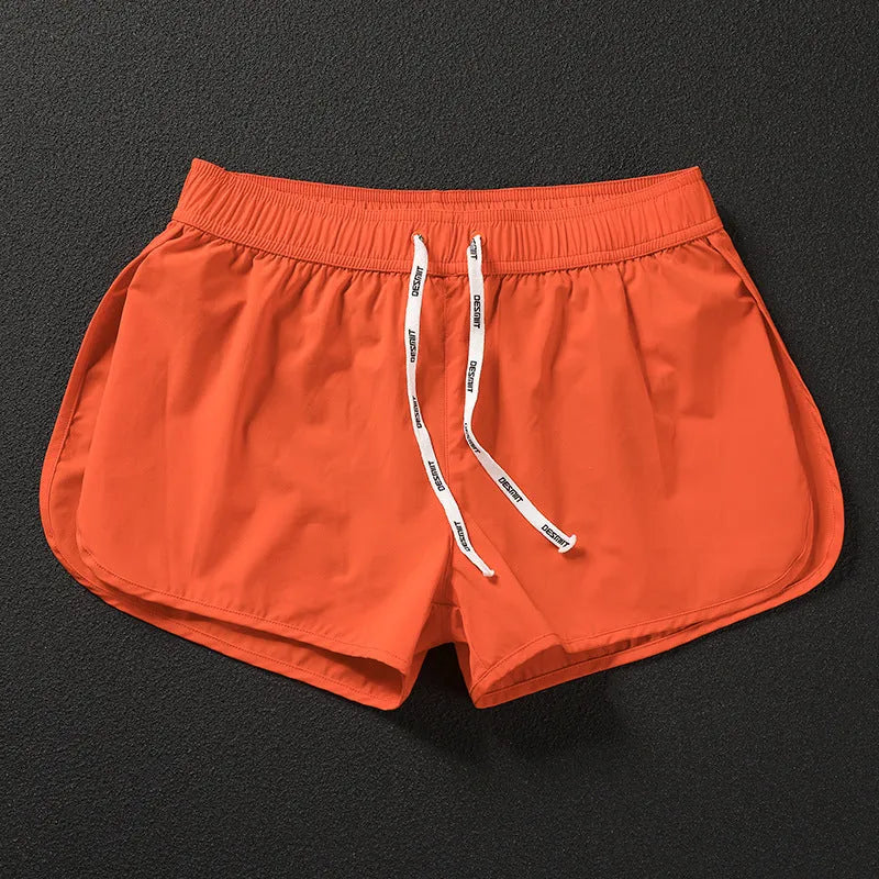 Man wearing orange micro-elastic polyester beach shorts for surfing or swimming.