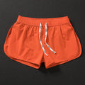Man wearing orange micro-elastic polyester beach shorts for surfing or swimming.