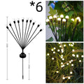 Solar-powered LED garden ground light with stainless steel spike, lit up in a lawn at dusk.