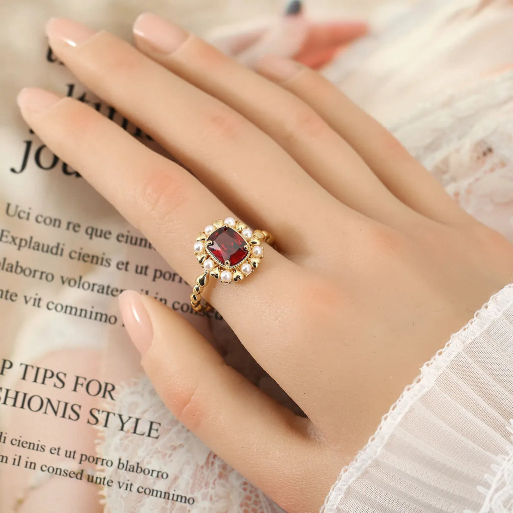 Gold electroplated ring with garnet red heart stone and geometric zircon setting.