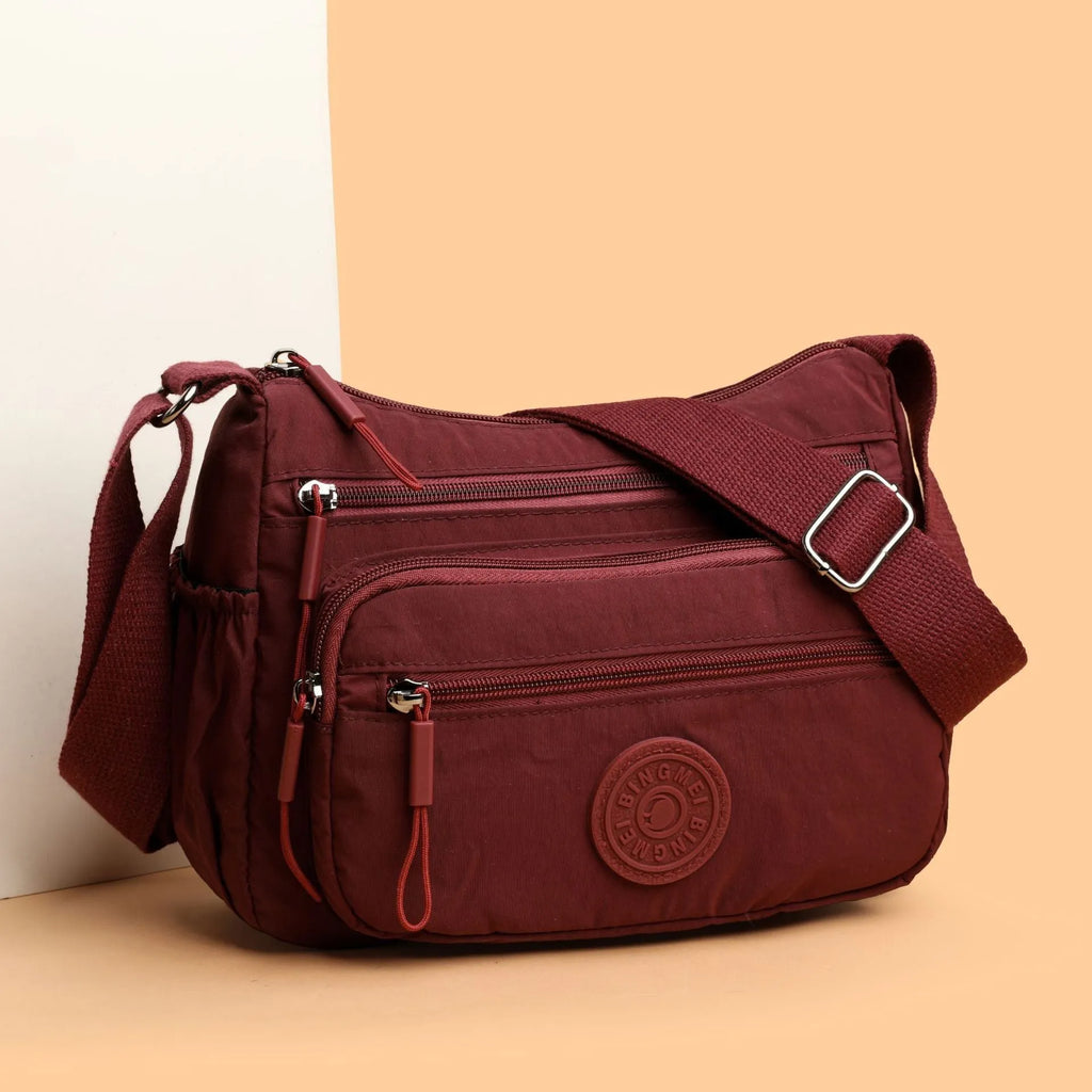 Soft water-repellent nylon crossbody bag in black with an outer pocket and zipped main compartment.