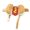 Small dog wearing a funny brown and beige full-body hot dog costume with bun sleeves.