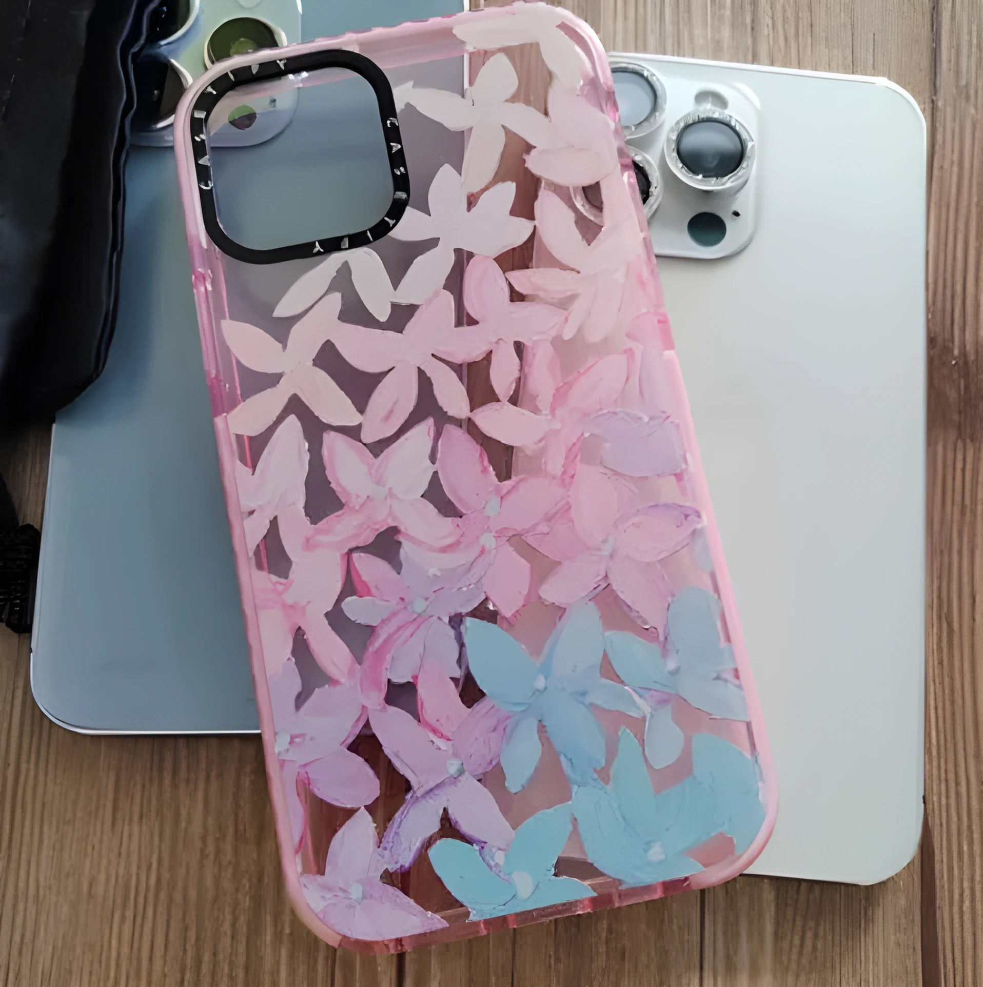 Transparent TPU phone case with pink and blue petal pattern for iPhone showing fall prevention feature