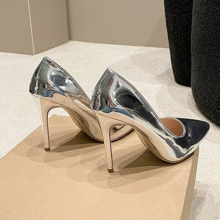 Gold and silver pointed toe slip-on stiletto heel pumps on a plain background
