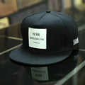 Adjustable unisex baseball cap in cotton polyester with short brim, available in black or white