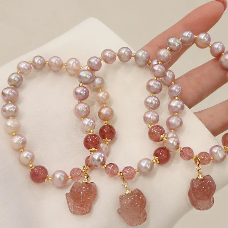 Light pink women's bracelet with freshwater pearls, strawberry quartz beads, and a silver fox charm on a white background.