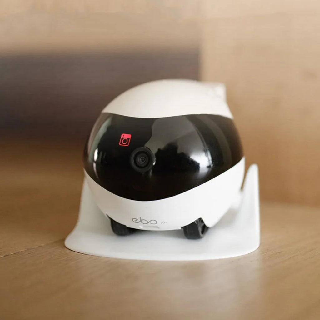 White smart home mobile robot camera on a charging dock.