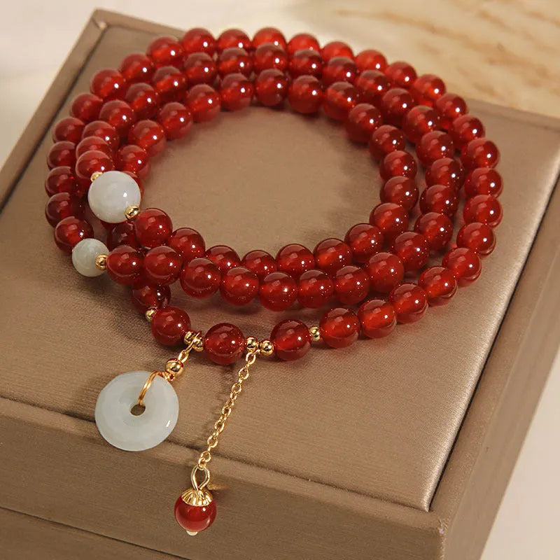 Women's multi-layer red agate crystal bracelet with adjustable closure on a wrist.