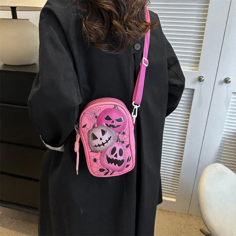 Black mini square crossbody bag with orange cartoon pumpkin, white ghost, and black bat graffiti print.