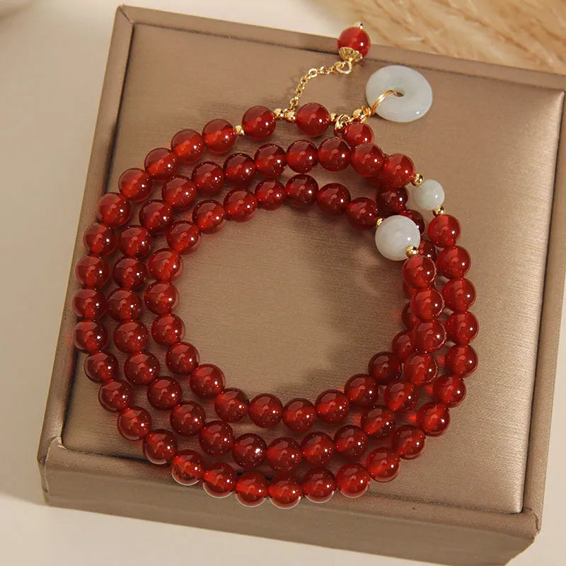 Women's multi-layer red agate crystal bracelet with adjustable closure on a wrist.