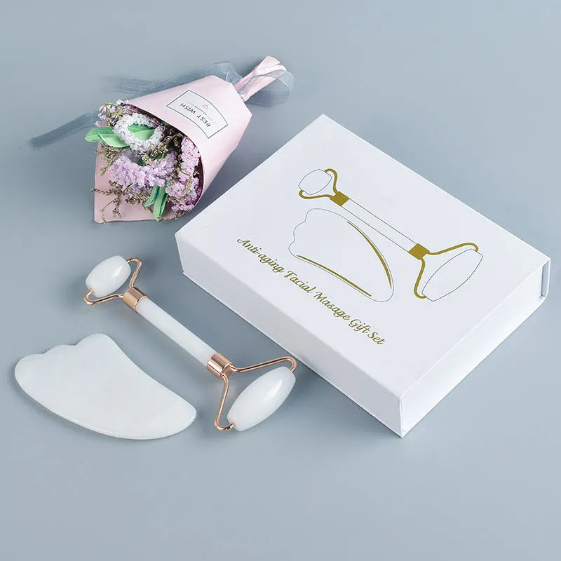 White jade double-headed facial roller and gua sha board set on a plain background.