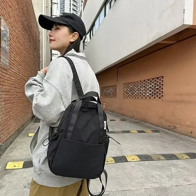 Solid colour nylon backpack in blue with curved straps and a lock, shown in a travel setting.