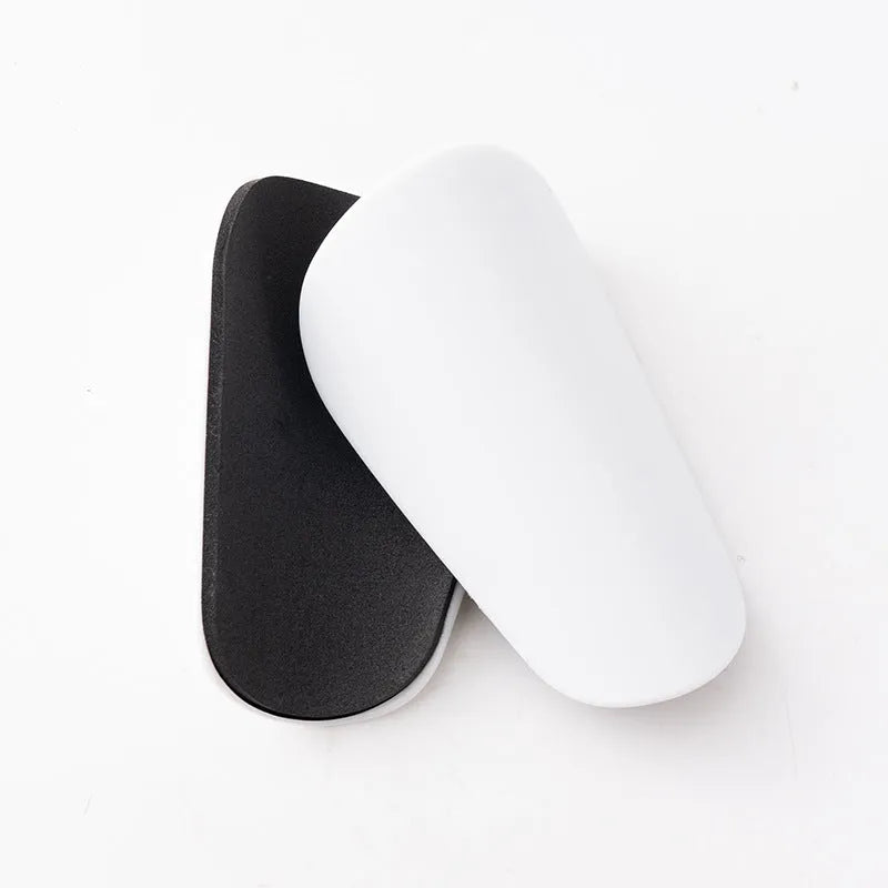 Pair of PU mini shin guards in black, shown on a leg, for football and sports protection.