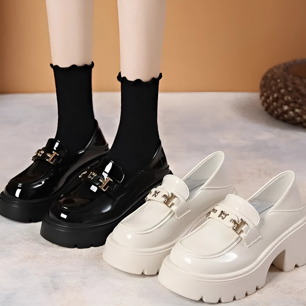 Black leather slip-on shoes with chunky square heel, round toe, and skull pattern design.