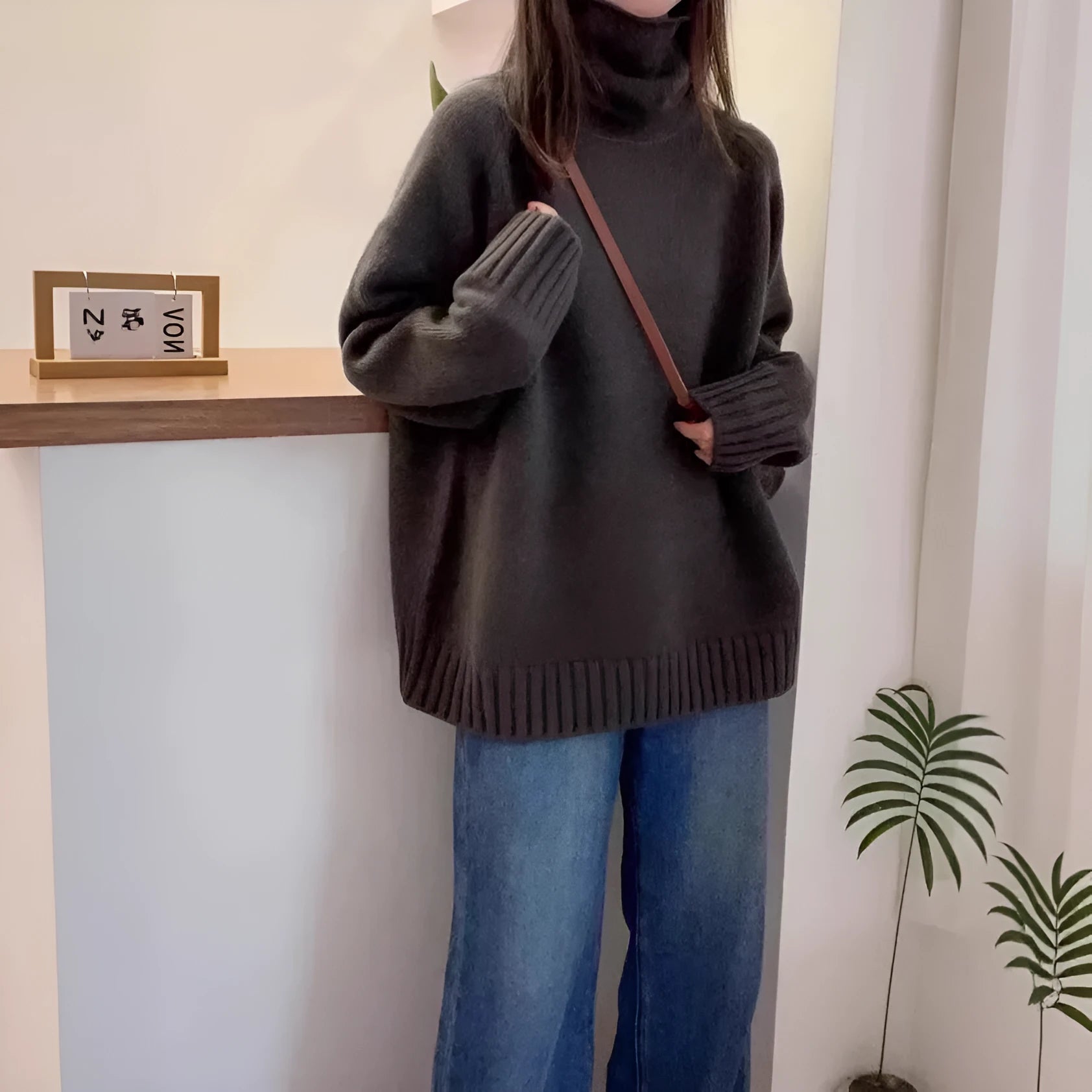 Women's loose grey turtleneck sweater with a thick curling pile collar and 3D pattern texture.
