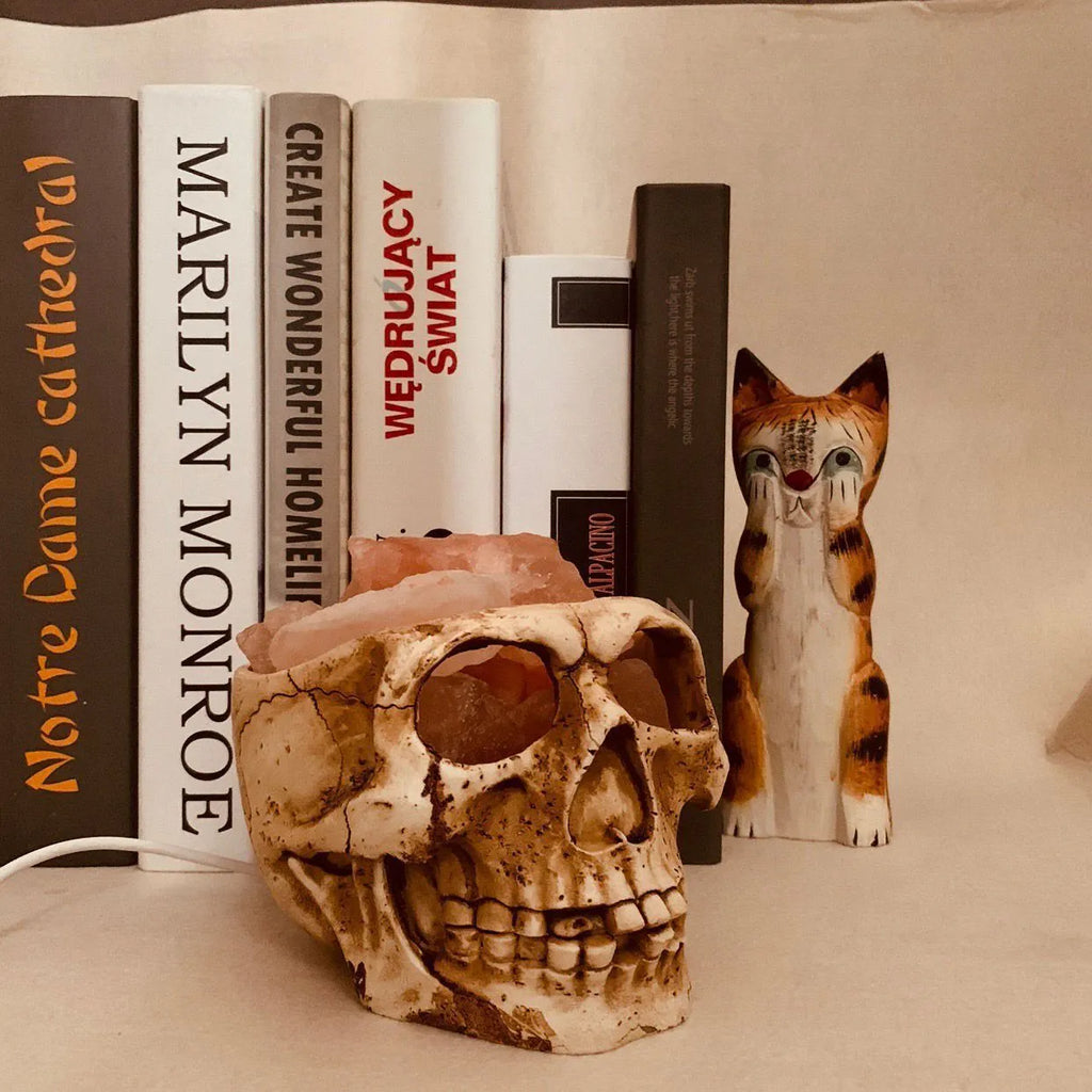 Skull-shaped Himalayan crystal salt lamp with USB dimmable LED showing warm amber light on a resin base