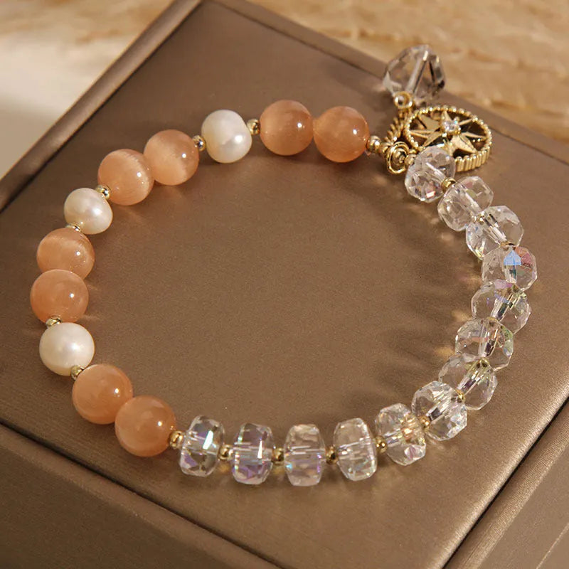 Gold-plated women's bracelet with an eight Awn star charm holding an inlaid orange opal crystal.