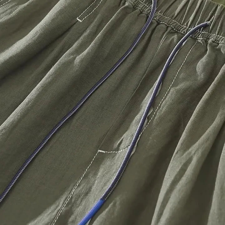 Man wearing loose fit green linen shorts with a straight leg and drawstring waist for casual summer wear.