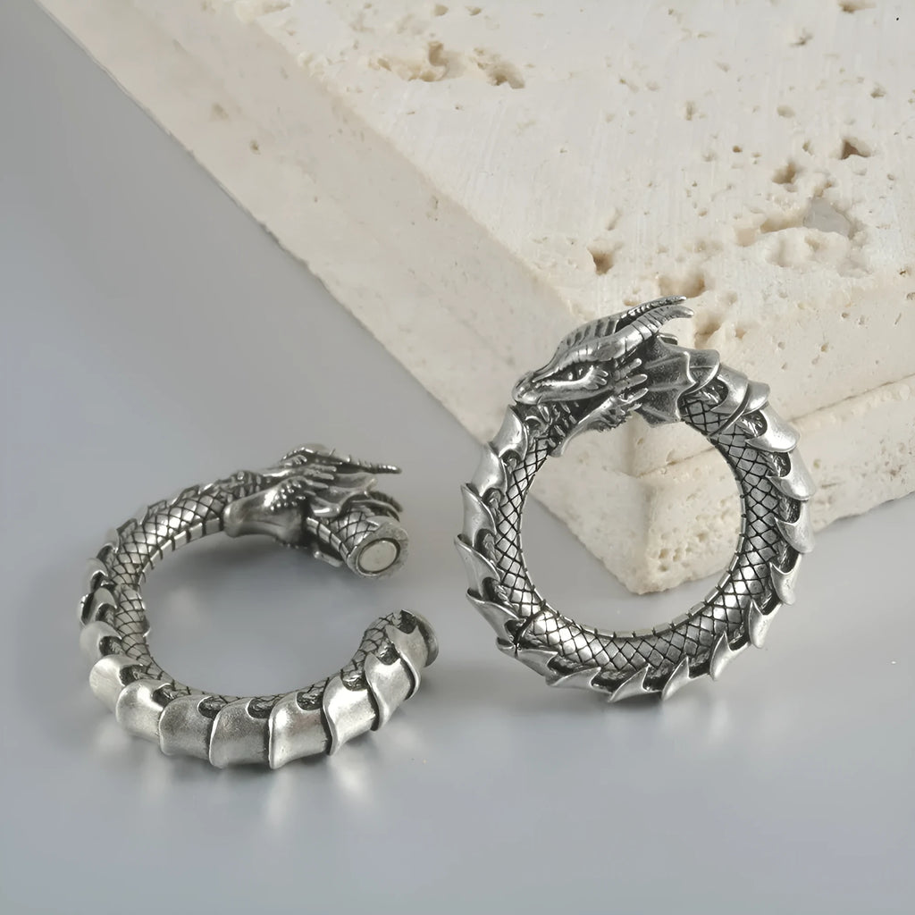 Pair of large antique silver dragon-shaped earrings with geometric hollow-out design on a white background.