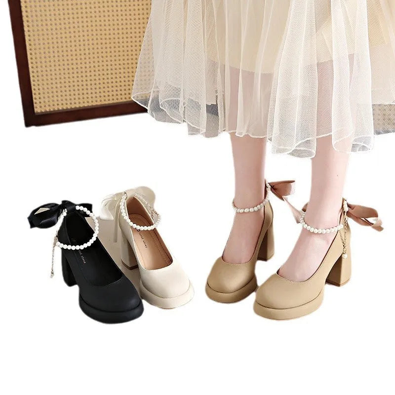 Women's beige Mary Jane shoes with chunky heel and silver ankle strap buckle on a wooden floor.