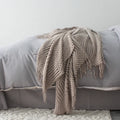 Small grey polyester nap blanket folded, showing its 127x170cm size on a sofa.