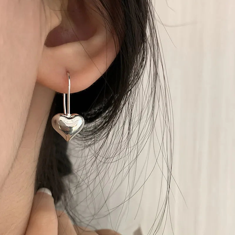 Silver Korean style heart-shaped earrings with a glossy three-dimensional design on a white background.
