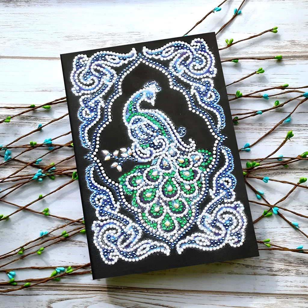 Peacock Beauty A5 diamond painting notebook with coloured resin drills on a black cover.