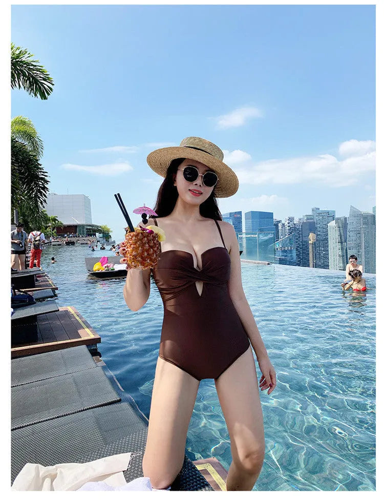 Simple solid colour one-piece swimsuit with spaghetti straps and push-up design in white, pink, or brown.
