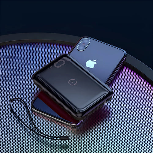 Small square black portable power bank with LED digital display on a table.