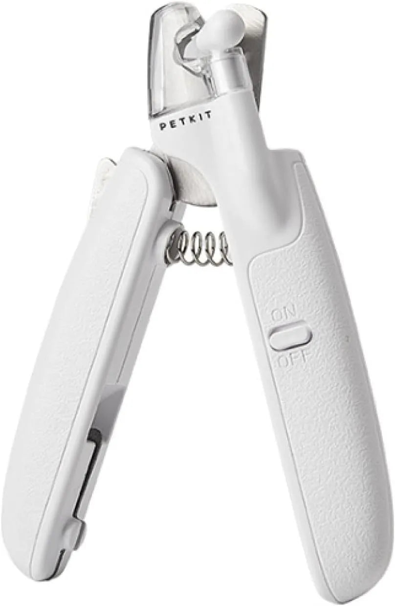 White pet nail clippers with LED light and transparent guard, shown with a separate nail file on a table.