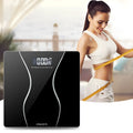 Black digital electronic bathroom scale with tempered glass platform on a bathroom floor.