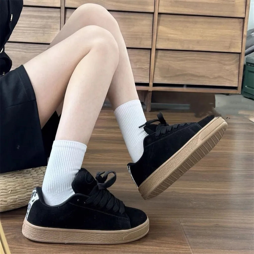 Black retro low-top sneakers with round toe and front lace-up closure on injection-moulded rubber sole