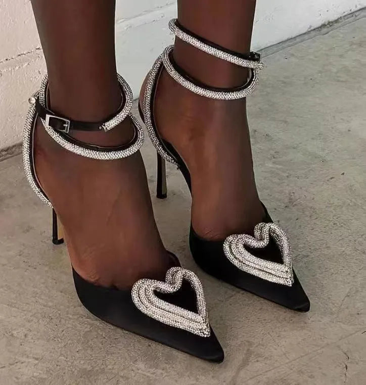 Women's fashionable black satin sandal with heart-shaped rhinestone and adjustable cross-belt strap.