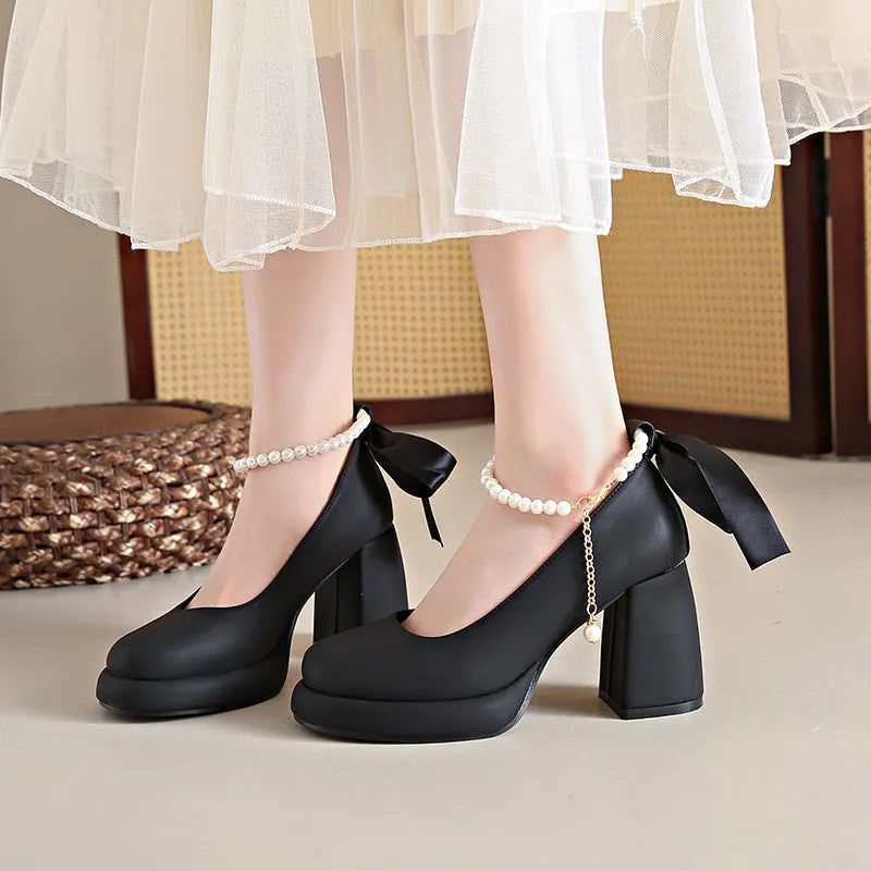 Women's beige Mary Jane shoes with chunky heel and silver ankle strap buckle on a wooden floor.