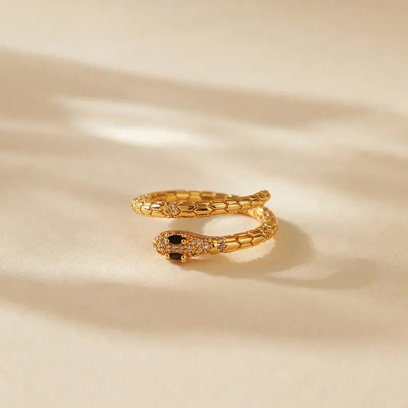 Snake-shaped adjustable copper ring with gold colour finish on a model's index finger.