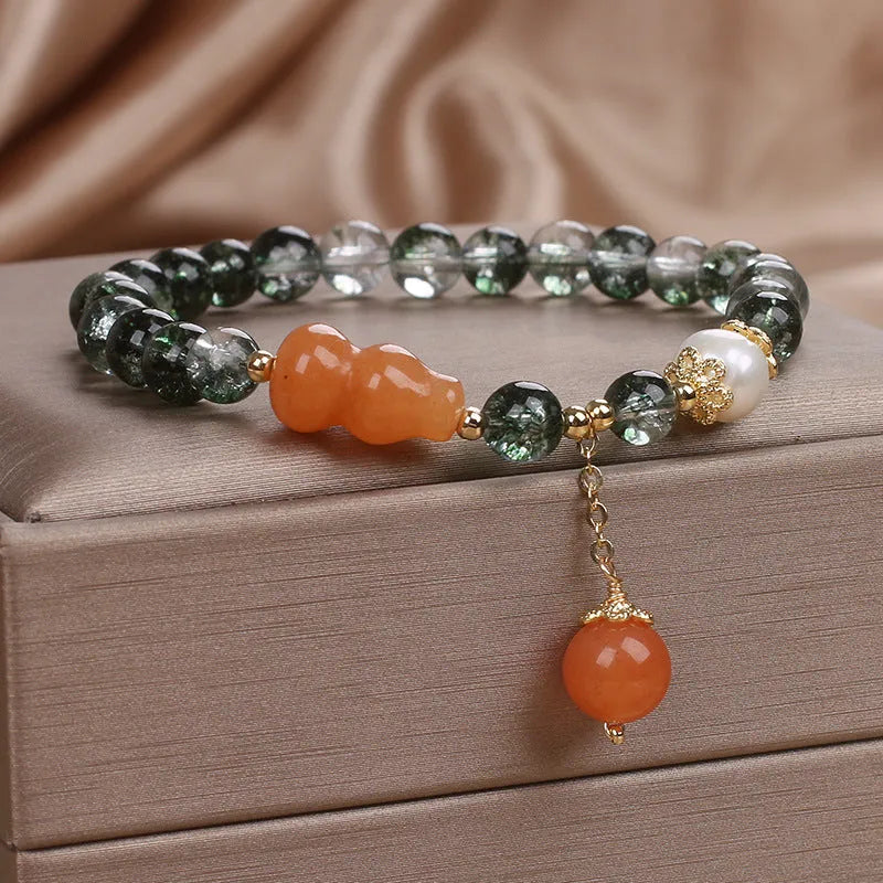 Green phantom quartz crystal bracelet with pearl and rhinestone accents on women's wrist