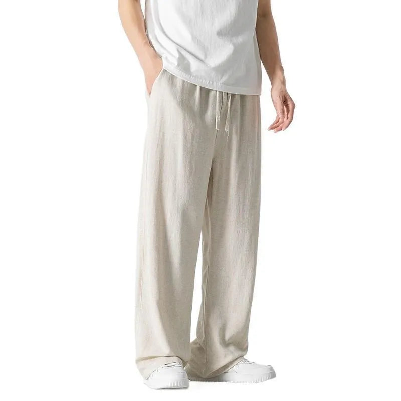 Man wearing beige loose-fit cropped straight-leg trousers made from bamboo fibre with a drawstring waist.